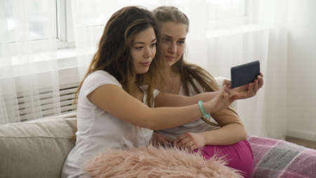 selfie modern youth lifestyle. online posting social network concept. friends leisure. young girls taking photo at homeの写真素材