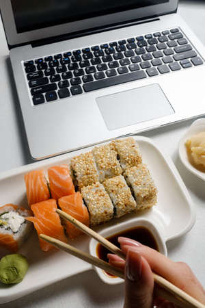 Food delivery service. Sushi rolls assortment fresh from a restaurant. Laptop online meal orderの写真素材