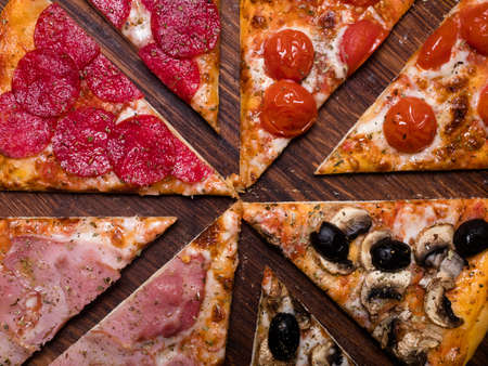 pizza background. national italian food meal. quattro stagioni with ham prosciutto tomatoes olives and mushrooms toppingの写真素材