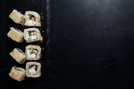 sushi eel rolls in sesame seeds on dark background. Food photography creative art. Free space conceptの写真素材