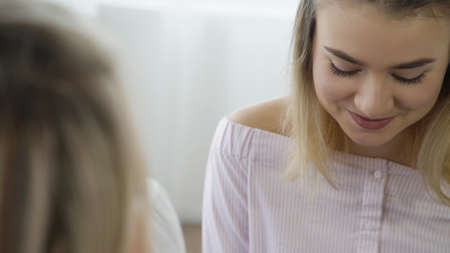 communication conversation. girlfriends at home chatting. young teenage girl looking down, shy and timidの写真素材