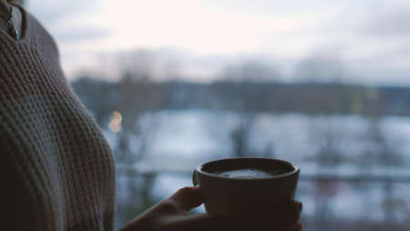 comfort relaxation leisure. evening cup of hot beverage. girl drinking tea at home at dusk. romantic calm twilight atmosphereの写真素材