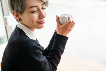 coffee or tea delight. woman enjoying a cup of hot drink. girl treating herself to a delicious hot beverageの写真素材