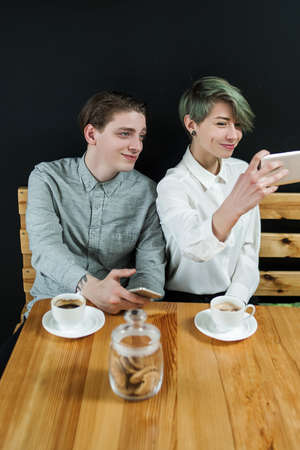 friends hangout at coffee shop or bar. couple date. modern youth leisure. girl taking a selfie with her boyfriend.の写真素材