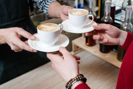 coffee bar service. client taking two cups of fresh hot tasty cappuccinoの写真素材