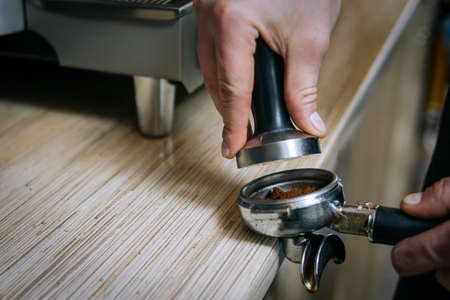 coffee shop professional equipment. barista using tamper to press coffee powder in the holder.の写真素材
