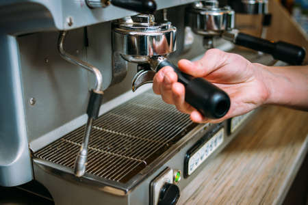 coffee brewing process. professional barista putting coffee powder in the holder into the machineの写真素材