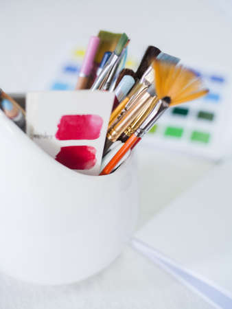 Professional makeup artist workplace. Closeup of color palette and set of brushes and pencils white...