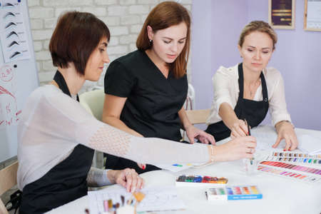 decorative cosmetology theoretical class. Ladies studying colors, using palette, paint and brushes.の写真素材