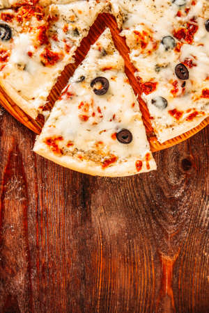 Italian restaurant. Traditional menu. Sliced pizza on brown rustic wooden background.