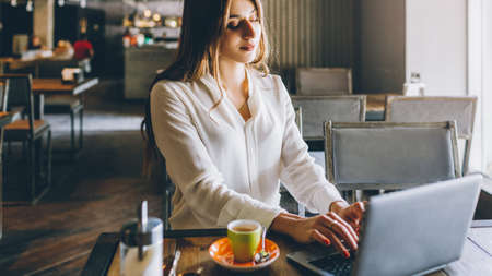 Freelancer lifestyle. Online job. Relaxed business woman working on laptop in coffee shop.の写真素材