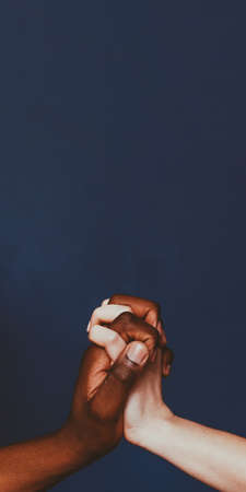 Social diversity. Ethnic tolerance acceptance support. African Caucasian people holding hands.の写真素材