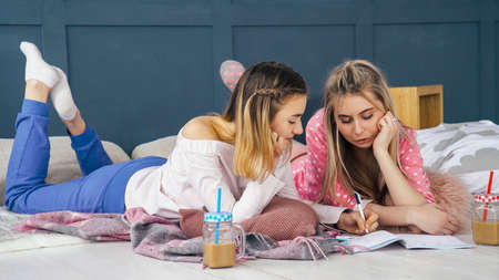 Women leisure. Relaxed lifestyle fun. Girls hanging out on floor at home drawing chatting.の写真素材