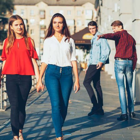 Sexual tolerance. Judgement mockery shame. Men staring at lesbian women walking holding hands.