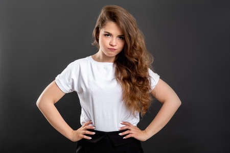 Displeased woman portrait. Indifference disappointment. Annoyed lady with hands on hips isolated on gray.の写真素材