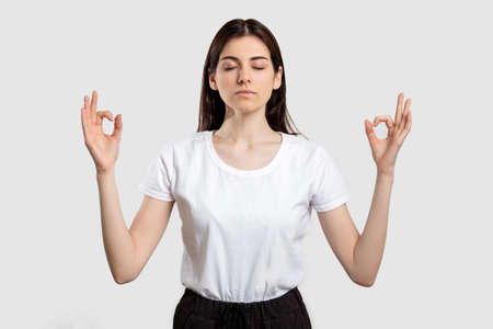 Yoga portrait. Zen patience. Calm woman meditating with closed eyes isolated on neutral background.