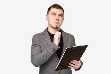 Startup idea. Marketing strategy. Pensive business man with clipboard thinking on project isolated on white.の写真素材
