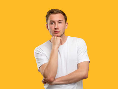 Puzzled man portrait. Tough decision. Concerned guy thinking on idea isolated on orange background.の写真素材
