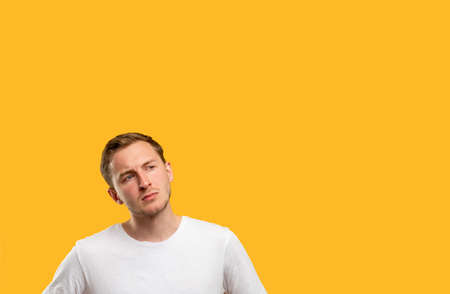 Curious man portrait. Promotional background. Pensive guy isolated considering offer on orange copy...