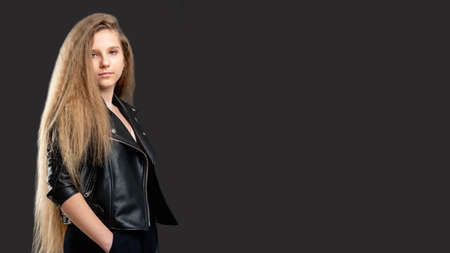 Youth lifestyle. Advertisement background. Confident teen girl with long hair standing isolated dark...