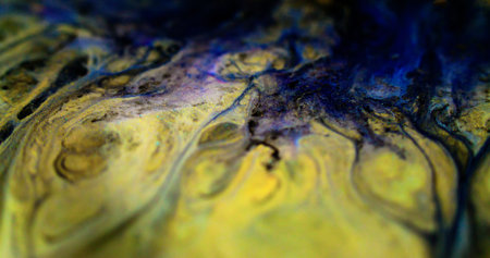 Glitter fluid drip. Shiny ink. Defocused black blue yellow color metallic shimmering dust particles oil emulsion dye paint spill abstract art background.の写真素材