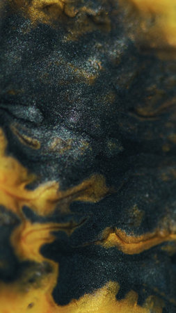 Ink spill. Glitter fluid mix. Defocused black golden yellow color shimmering wet paint flow bokeh...