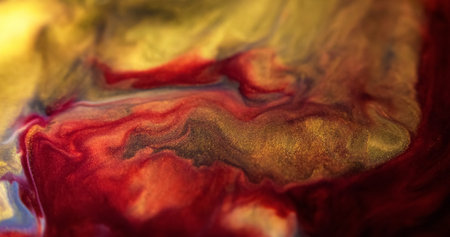 Glitter paint wave. Shiny liquid. Defocused red golden color metallic sparkling grain particles...