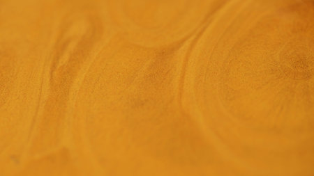 Liquid glitter flow. Sparkling paint texture. Blur orange golden color metallic shimmering sand particles acrylic fluid pigment ink spill abstract art background.の写真素材