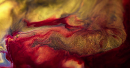 Sparkling ink. Glitter paint drip. Defocused red blue golden color metallic sequin shiny dust particles texture pigment emulsion fluid flow motion abstract art background.の写真素材