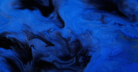 Ink spill. Glitter fluid mix. Defocused blue black color glowing sparkling marble texture acrylic wave decorative dark abstract art background.の写真素材