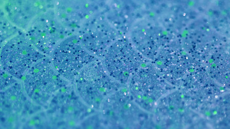 Glitter fluid drip. Shiny gel texture. Blur blue color sparkling sequin grain particles in translucent liquid water emulsion spill abstract art background with bokeh lights.の写真素材