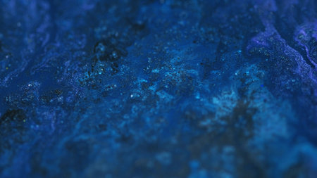 Shiny liquid. Glitter ink spill. Defocused blue color sparkling grain particles acrylic paint fluid water pigment mix flow abstract art background.の写真素材