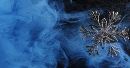 Abstract winter ornament. Snowflake mist. Blue color paint water smoke cloud revealing shiny glitter...