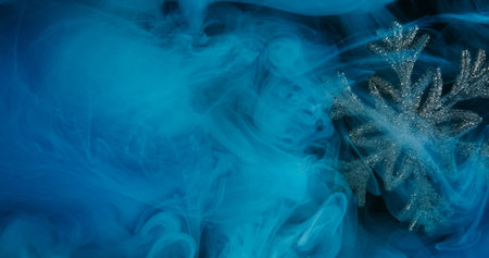 Snowflake background. Smoke cloud. Shimmering silver Christmas ornament on blue color glitter ink water splash abstract texture.の写真素材