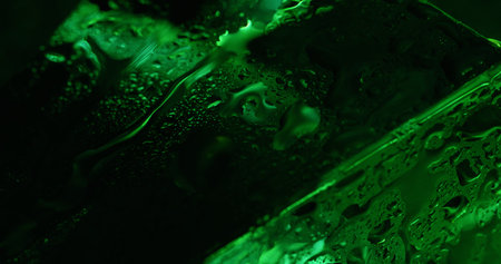 Blur moisture. Wet green. Flow on smooth surface wavy jets. Macro pouring water with spectral...