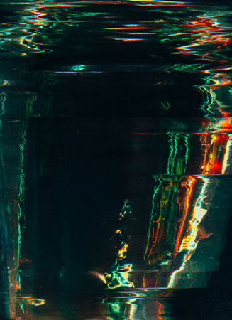 Damaged film. Distressed foil overlay. Green orange color flare glitch artifacts water surface reflect light effect scratch texture dark illustration art abstract background.の写真素材