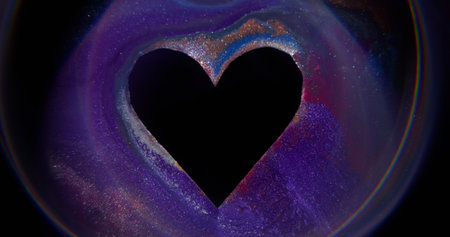 Gleaming paint. Color heart. Defocused purple red black shape love frame ink texture spill on abstract art romantic dark background.の写真素材