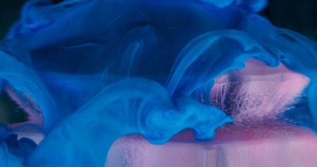 Mystical smoke. Hypnotic fluid. Pink violet blue smooth curl paint floating on glass blue crystal...