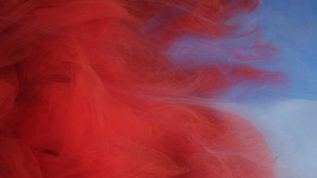 Color splash. Magic smoke. Defocused red glowing vapor paint ink texture haze floating on blue abstract art light background.の写真素材