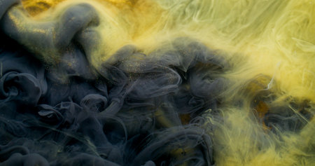 Ink stream. Dye spread. Yellow liquid color paint explosion flow. Art fume wave blend abstract blur black golden glitter background.の写真素材