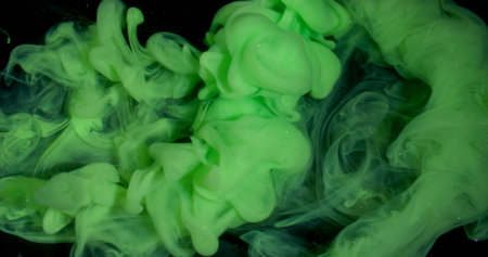 Smoke stream. Dye spread. Bright color green paint explosion flow. Art fume wave spray abstract blur black sparkling water background.の写真素材