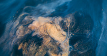 Sparkling flow. Ink mix. Golden black acrylic stream wave blend. Art liquid spilling color wet texture defocused abstract background.の写真素材