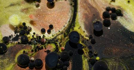 Oil bubbles. Glitter paint. Defocused yellow orange color sparkling dark black texture blend water floating on abstract bokeh art background.の写真素材