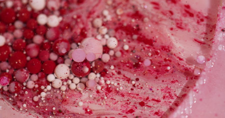 Oil bubbles. Paint fluid. Defocused red pink white colorful sparkling glitter particles flow...