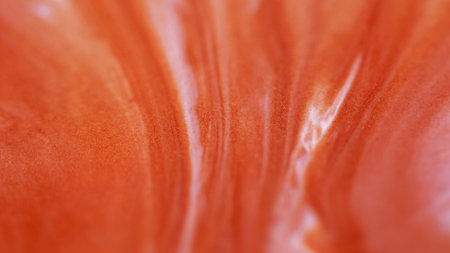 Spilling paint. Shiny fluid. Defocused orange white color chemical enamel water wet marble texture flow floating on abstract background.の写真素材