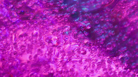 Glow drop. Liquid light. Defocused blue pink neon colorful water texture fluorescent flow pouring on...