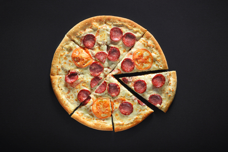 home pizza with pepperoni, tomato, carbonate, mozzarella on black stone backgroundの写真素材