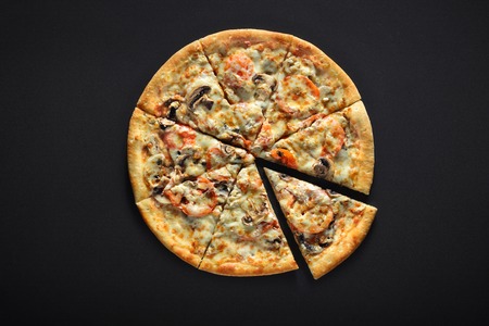 Fresh italian pizza with mushrooms, tomatoes, cheese, on black stone backgroundの写真素材