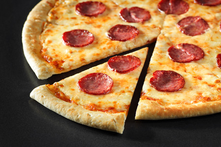 cut Pizza close up peperoni on black stone backgroundの写真素材