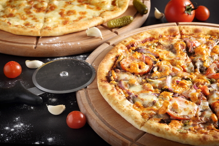 Traditional Italian pizza on a dark background with a pizza knifeの写真素材